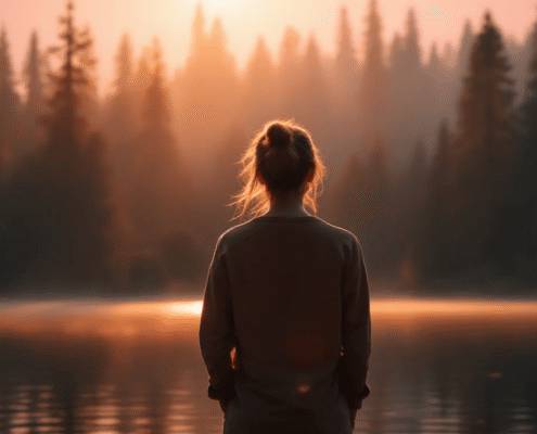 A person stands peacefully by a serene lake at sunrise, embodying self-reflection and the journey of personal growth.