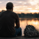Military veteran sitting by a lake at sunset, representing mental health challenges during transition to civilian life
